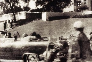 El primer disparo es desviado por un árbol y rebota en el cemento que hiere al testigo James Tague. 3,5 segundos después se produce el segundo disparo que llega a Kennedy por detrás y sale por su garganta, hiriendo también al gobernador de Texas, John Connally. El presidente deja de saludar al público y su esposa tira de él para recostarlo sobre el asiento. El tercer disparo ocurre 8,4 segundos después del primer disparo, justo cuando el auto pasa al frente de la pergola de hormigón. Cuando el tercer disparo impacta de lleno en el occipital derecho de la cabeza de Kennedy, Jackie Kennedy, se abalanza a la parte trasera del auto, donde recoge una sección del cráneo del presidente. Un ciudadano de nombre Abraham Zapruder, que filmaba la comitiva presidencial, logró captar en su película el momento en que Kennedy es alcanzado por los disparos. Esta película es parte del material que la Comisión Warren utilizó en su investigación del asesinato.